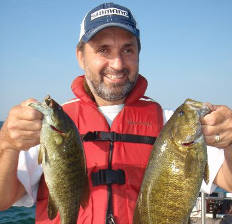 Smiling man holding two bass fish